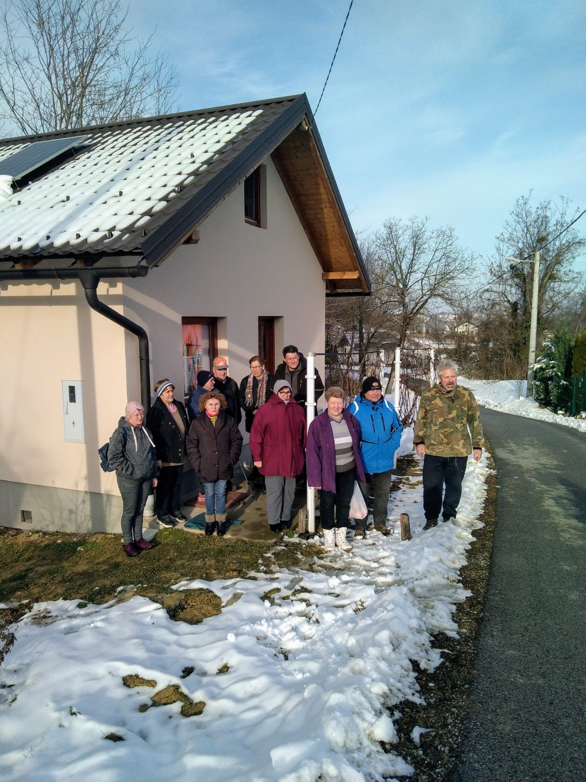 grupa ljudi ispred kuće